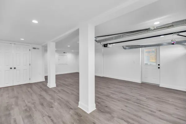an empty room with wooden floor closet and windows