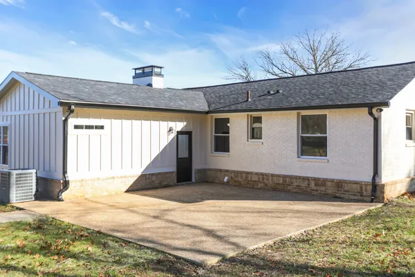 a view of a house with a yard and a large tree