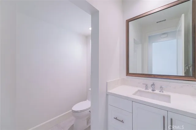 a bathroom with a granite countertop sink a toilet and a mirror