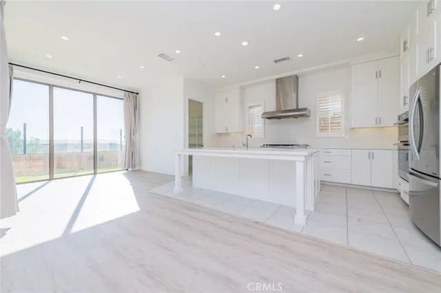 a large white kitchen with white cabinets and a refrigerator
