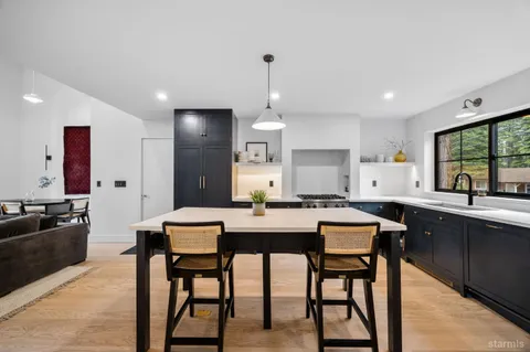 a kitchen with stainless steel appliances granite countertop a stove a sink a microwave a dining table and chairs with wooden floor