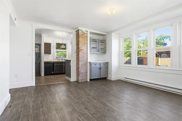 a view of an empty room with a window and wooden floor