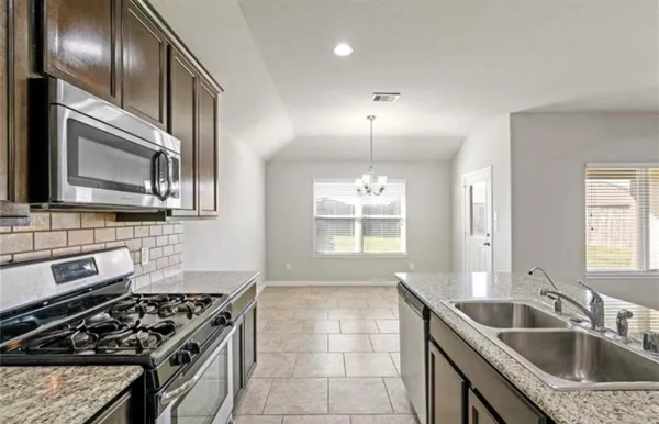 a kitchen with granite countertop stainless steel appliances a sink stove and cabinets