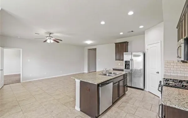 a large kitchen with stainless steel appliances kitchen island granite countertop a refrigerator a sink a stove top oven and a dishwasher