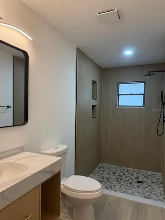 a bathroom with a sink a toilet a mirror and shower