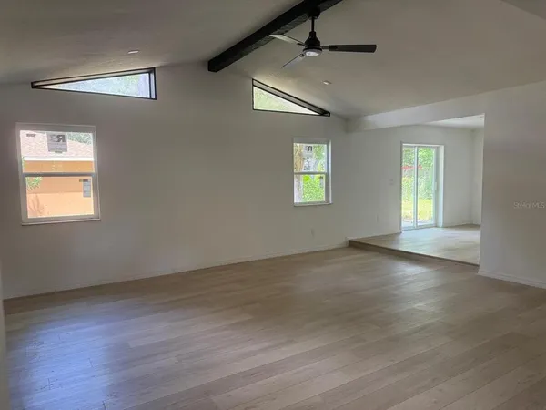 a view of an empty room with a window and wooden floor
