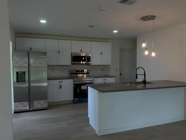 a kitchen with stainless steel appliances granite countertop a sink a stove a refrigerator and a refrigerator