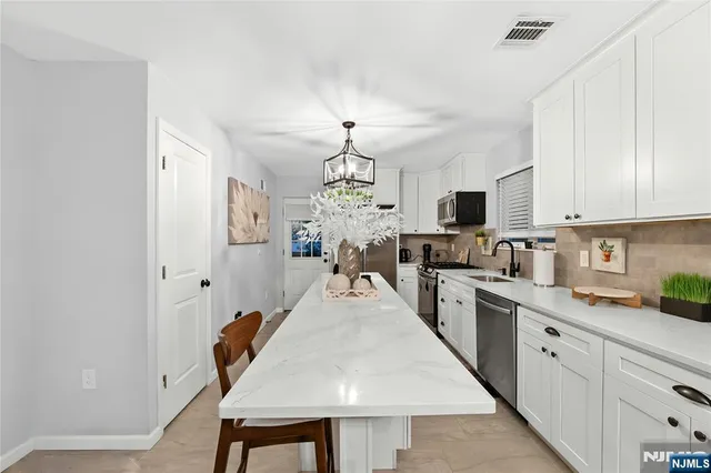 a kitchen with stainless steel appliances granite countertop a stove top oven a sink dishwasher and a refrigerator with wooden floor