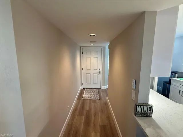 a view of a hallway with wooden floor and a bathroom space