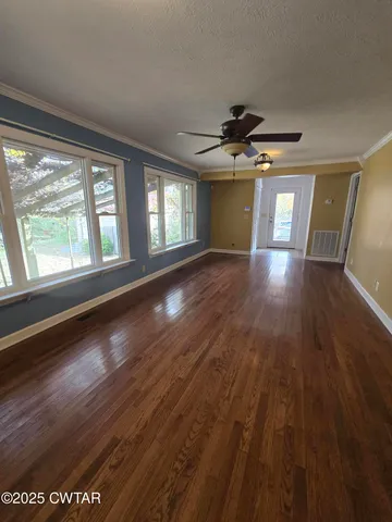 a view of an empty room with window and wooden floor