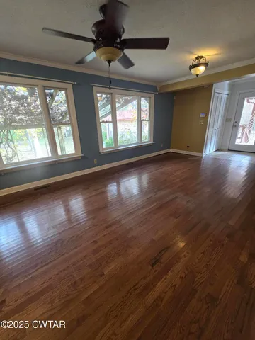 a view of an empty room with wooden floor and a window
