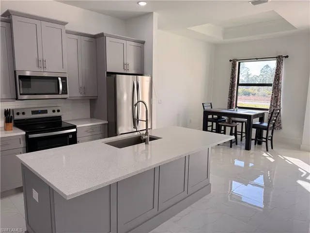 a kitchen with stainless steel appliances a white table chairs and a refrigerator