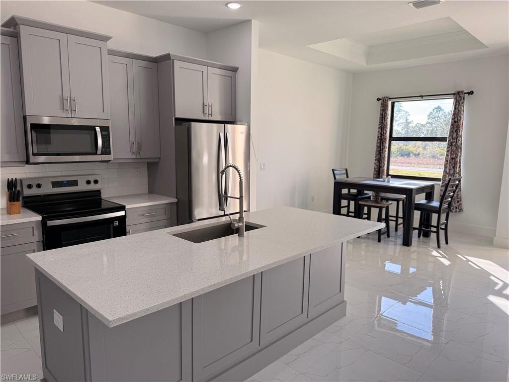 a kitchen with stainless steel appliances a white table chairs and a refrigerator