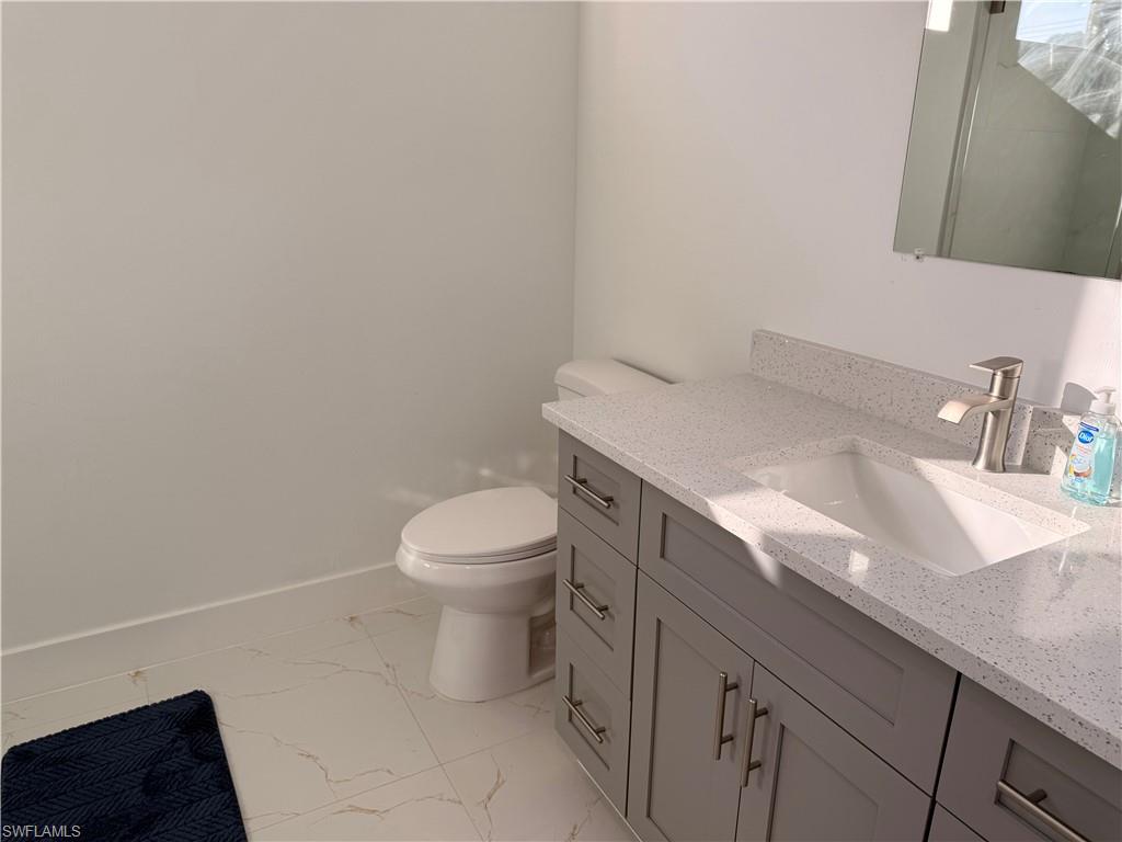 941 Columbus Boulevard Lehigh Acres, FL 33974 - Photo 15 of 41 a bathroom with a granite countertop toilet and sink