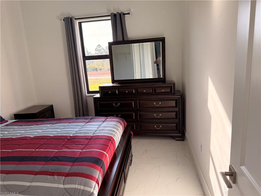 941 Columbus Boulevard Lehigh Acres, FL 33974 - Photo 17 of 41 a bedroom with a bed and a mirror on dresser
