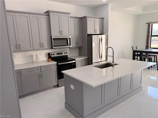 a kitchen with white cabinets sink and stainless steel appliances