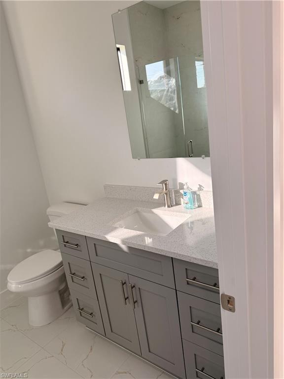 941 Columbus Boulevard Lehigh Acres, FL 33974 - Photo 20 of 41 a bathroom with a granite countertop toilet sink and mirror