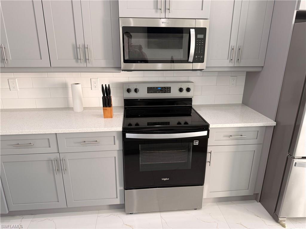 941 Columbus Boulevard Lehigh Acres, FL 33974 - Photo 4 of 41 a kitchen with stainless steel appliances granite countertop a stove microwave and cabinets