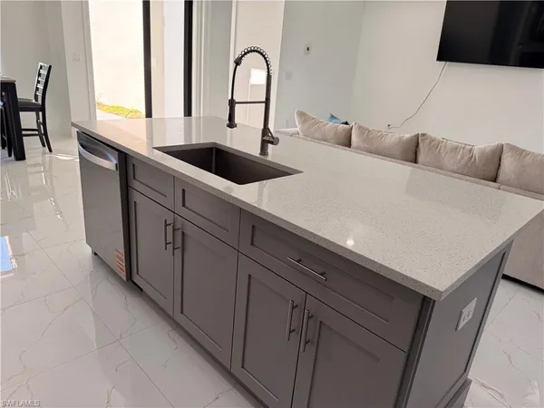 a living room with stainless steel appliances furniture a refrigerator and a kitchen sink