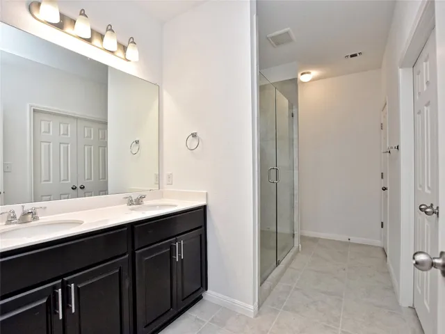a bathroom with a double vanity sink mirror and shower
