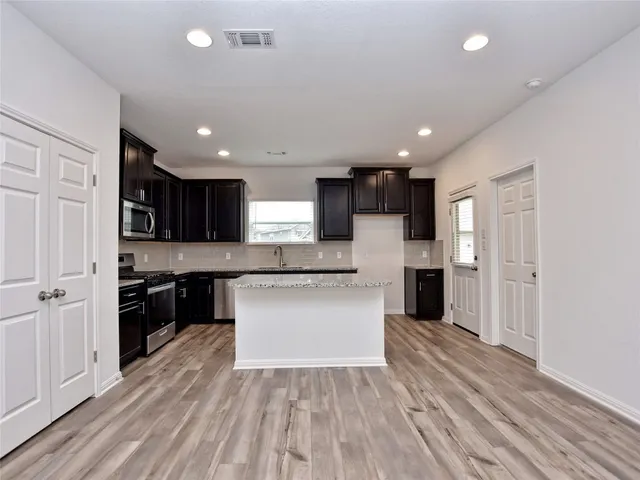 a view of kitchen with granite countertop stainless steel appliances refrigerator sink and cabinets