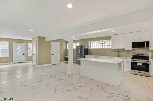 a large white kitchen with stainless steel appliances granite countertop a sink and cabinets