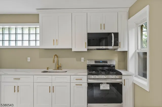a kitchen with stainless steel appliances granite countertop white cabinets and a stove top oven