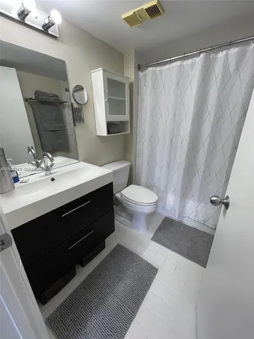 a bathroom with a sink a toilet a mirror and shower curtain