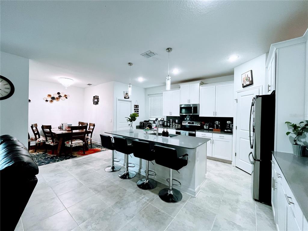 11498 Rhyme Avenue Orlando, FL 32832 - Photo 5 of 17 a kitchen with refrigerator and chairs in it