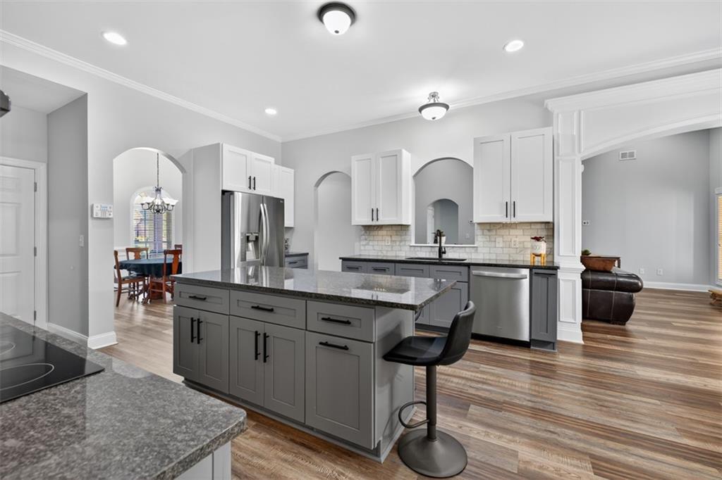 236 Reece Drive Hoschton, GA 30548 - Photo 13 of 58 a large kitchen with stainless steel appliances granite countertop a stove a sink dishwasher a dining table and chairs with wooden floor