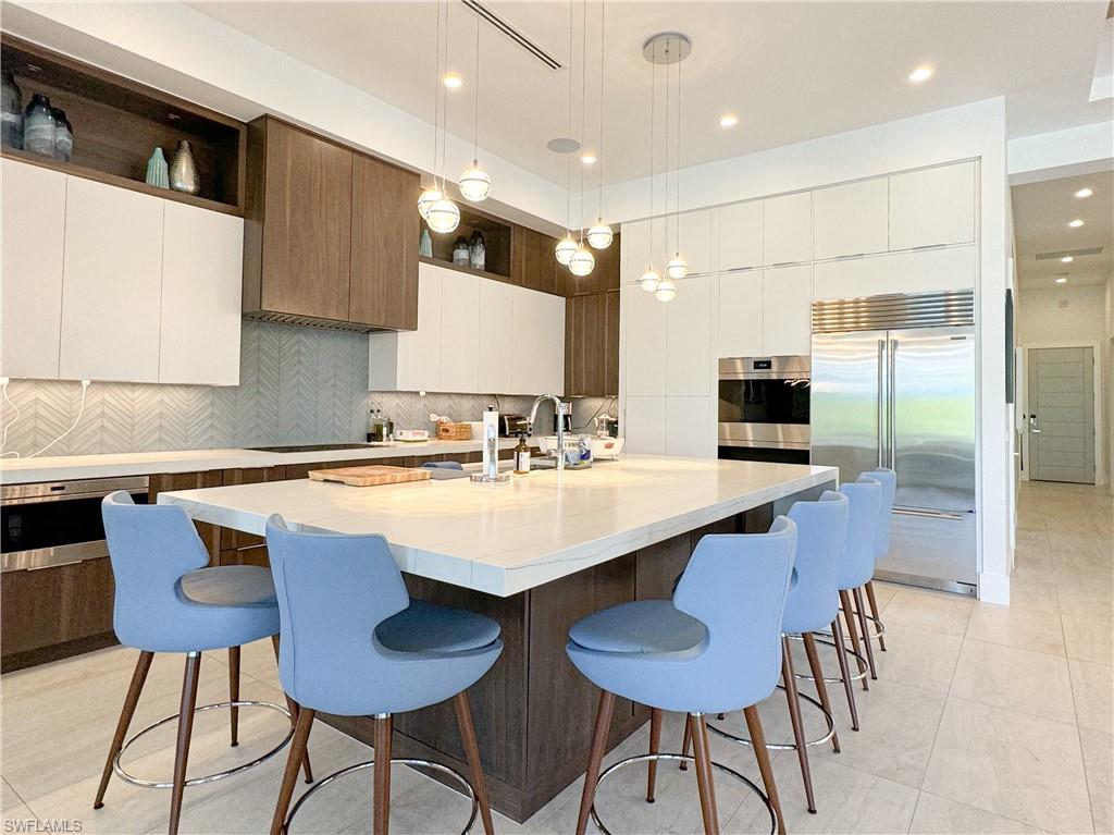 3123 Crayton Road Naples, FL 34103 - Photo 31 of 50 a kitchen with granite countertop a table chairs stove and cabinets