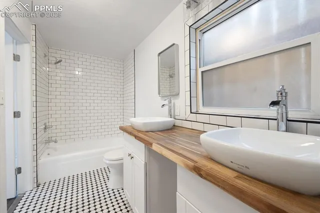 a bathroom with a granite countertop sink a toilet a mirror and shower