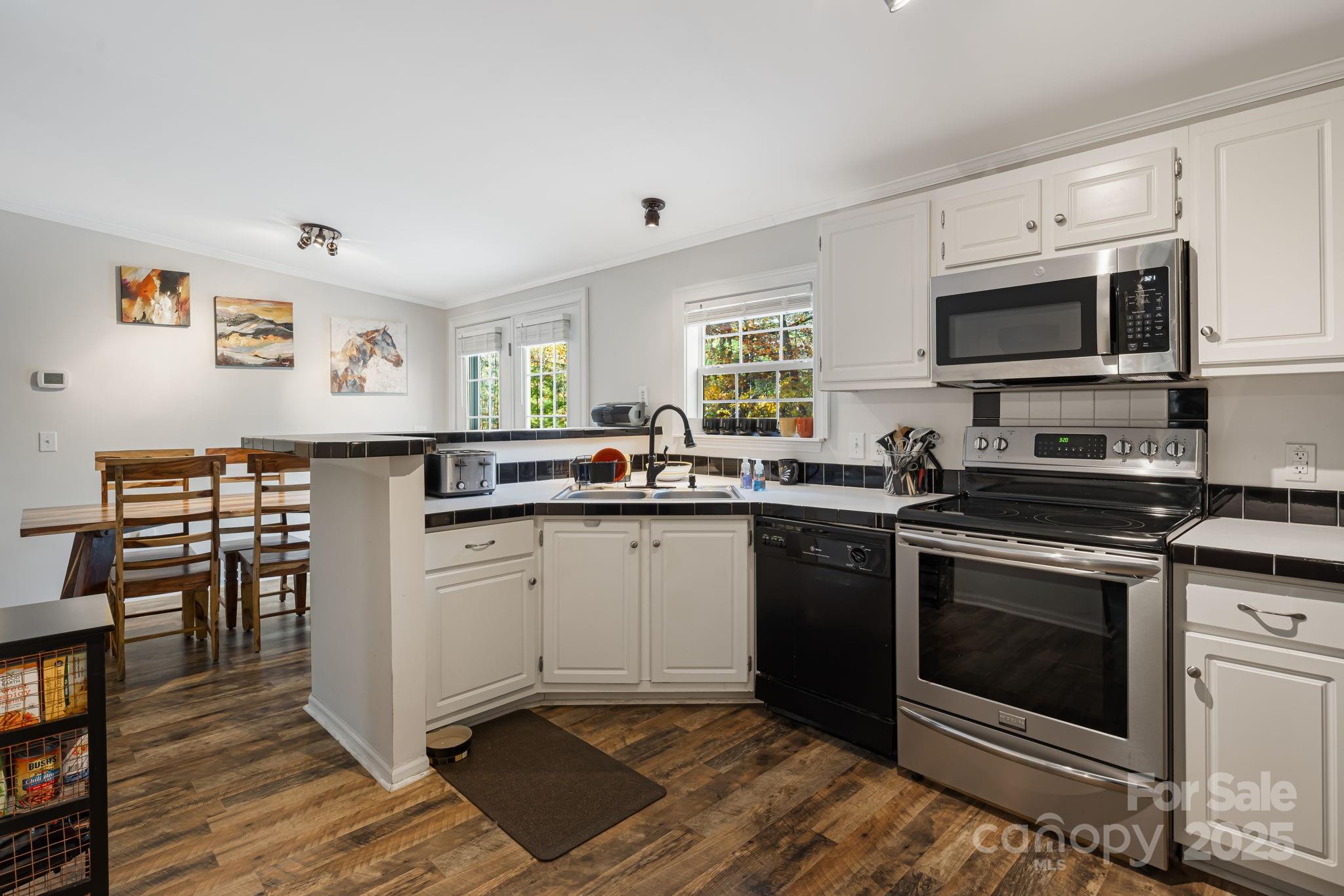57 Founders Way Arden, NC 28704 - Photo 9 of 26 a kitchen with stainless steel appliances granite countertop a stove top oven a sink dishwasher and white cabinets with wooden floor
