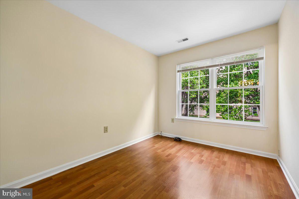 18012 Golden Spring Court, Unit 239 Olney, MD 20832 - Photo 33 of 44 an empty room with wooden floor and windows