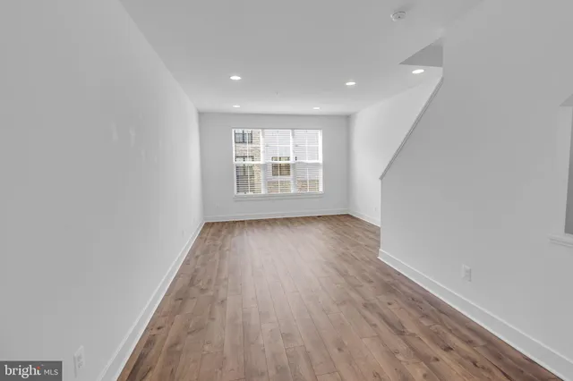 an empty room with wooden floor and window