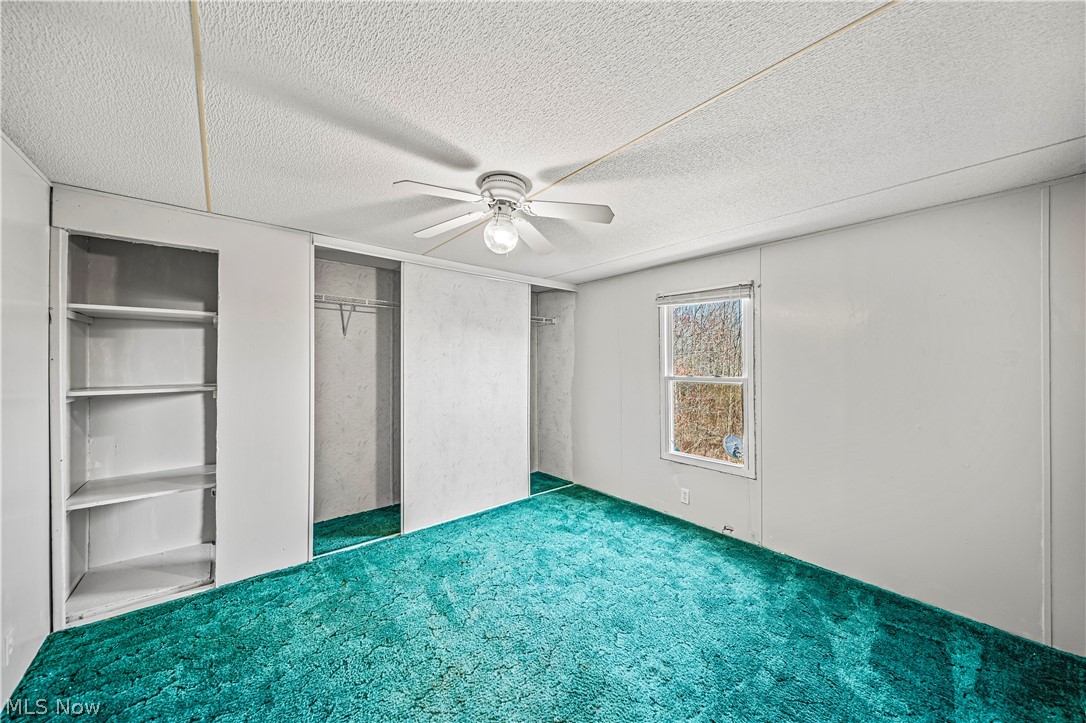 3471 Fox Road Kingsville, OH 44048 - Photo 23 of 50 Unfurnished bedroom featuring ceiling fan, a closet, dark carpet, and a textured ceiling