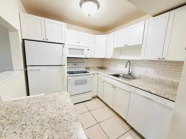 a kitchen with white cabinets and white appliances