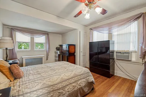 a bedroom with a bed and a dresser with wooden floor