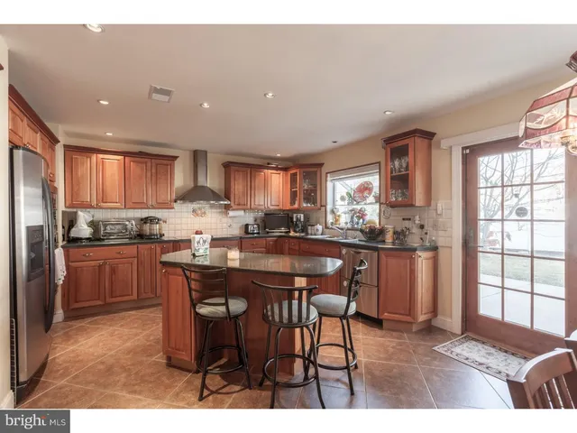 a kitchen with stainless steel appliances granite countertop a table chairs sink refrigerator and cabinets