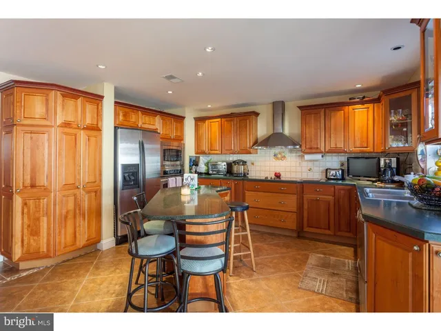 a kitchen with stainless steel appliances granite countertop a refrigerator a sink dishwasher a dining table and chairs with wooden floor