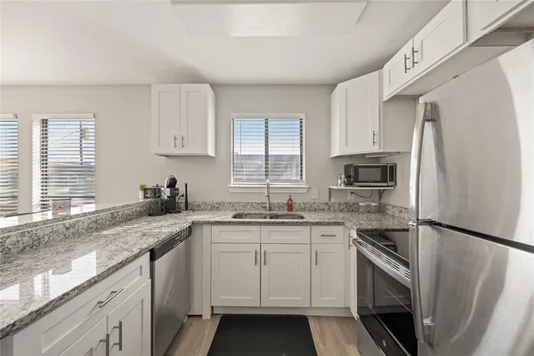 a kitchen with stainless steel appliances granite countertop a sink stove microwave and refrigerator