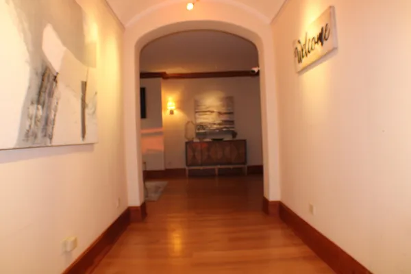 a view of a hallway with wooden floor and a bathroom