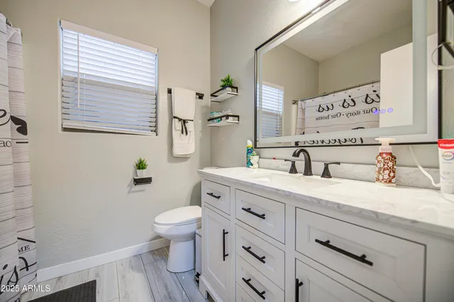 a bathroom with a granite countertop sink mirror vanity and toilet