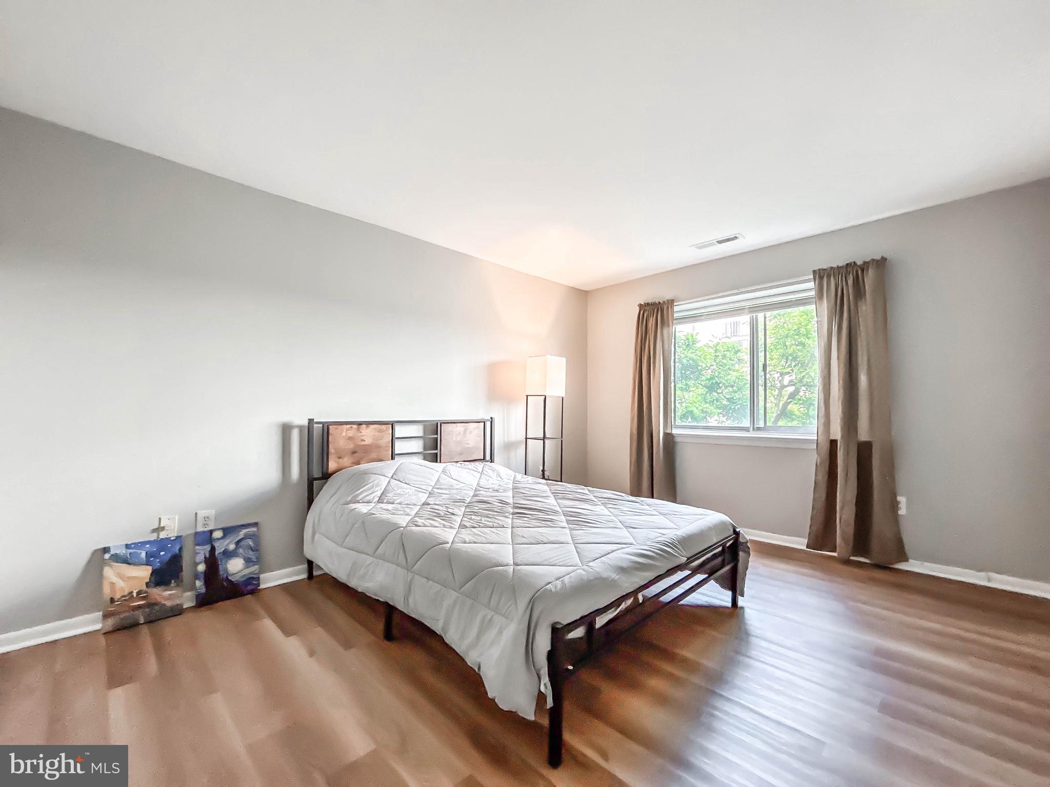 130 Slade Avenue, Unit 414 Baltimore, MD 21208 - Photo 23 of 48 a bedroom with a bed and wooden floor