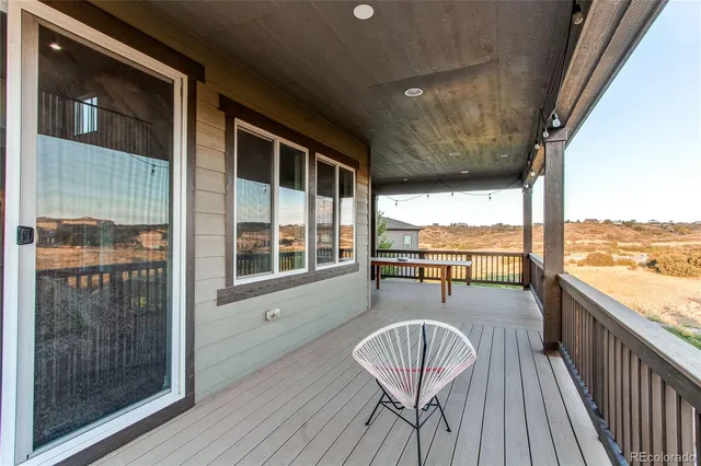 a balcony with wooden floor table and chairs