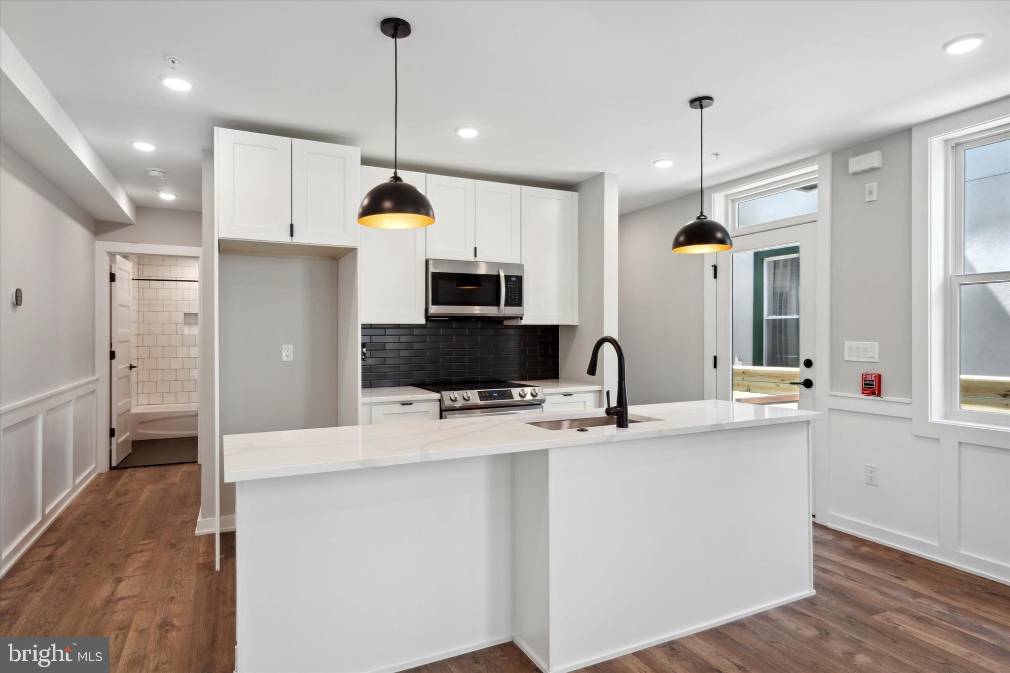 3519 Hamilton Street, Unit B Philadelphia, PA 19104 - Photo 6 of 16 a kitchen with kitchen island a white counter top space stainless steel appliances and a chandelier