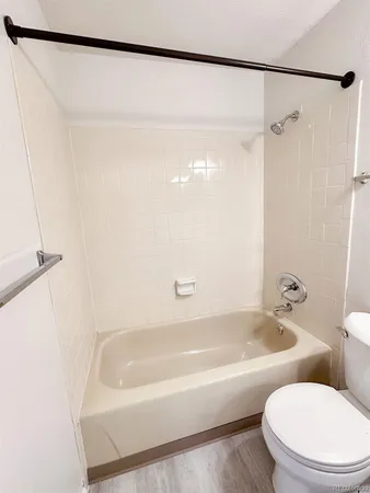 a white bath tub sitting next to a white toilet and a shower