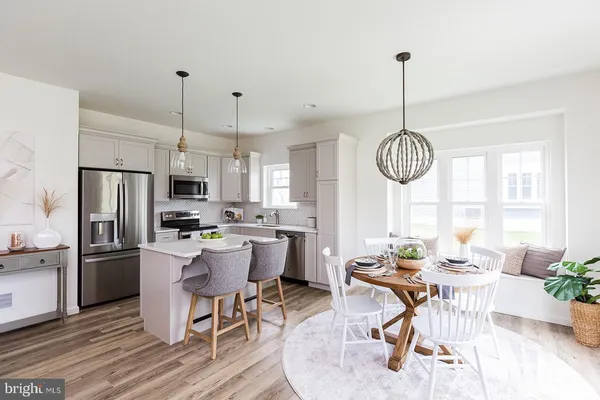 a kitchen with stainless steel appliances a dining table chairs stove and refrigerator