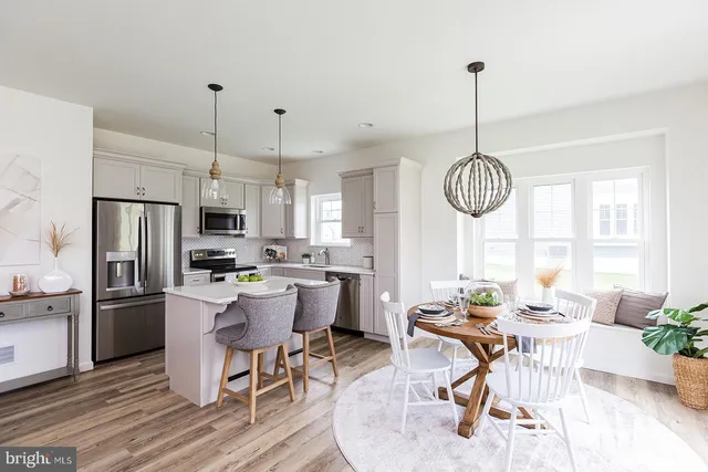 a kitchen with stainless steel appliances a dining table chairs stove and refrigerator