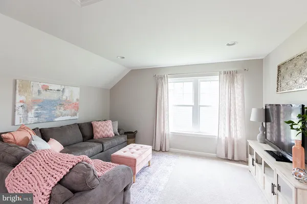 a living room with furniture a flat screen tv and a window